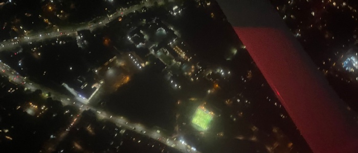 Arial photo of OSH site at night lit up with street lights, clearly showing boarding houses and sports pitches
